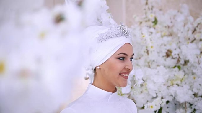 微笑的穆斯林新娘在鲜花中化妆