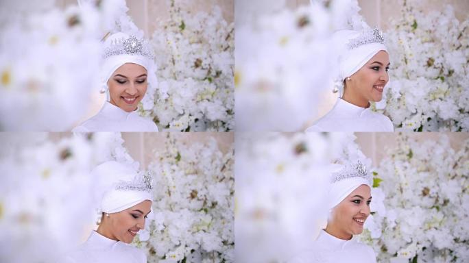 微笑的穆斯林新娘在鲜花中化妆