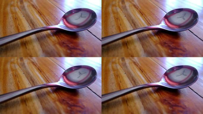工作风扇在勺子上的倒影在木桌上。
