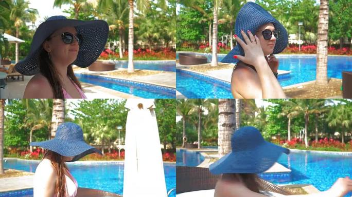 戴着蓝帽子的漂亮女孩走到泳池边的躺椅上。夏日阳光