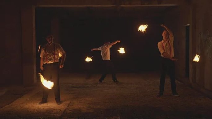 一群男性艺术家在黑暗中以慢动作表演火表演。