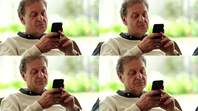 富有表现力的退休老人全神贯注于智能手机设备上的内容。坦率的真实生活中老人关注他的手机技术和4k电子邮
