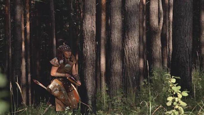 年轻的塔塔尔蒙古弓箭手射击弓箭，下午站在绿色森林中