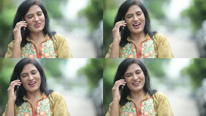 成熟快乐美丽的印度女人在户外街头思考时打电话