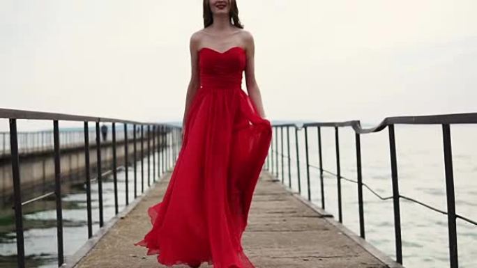穿着猩红色连衣裙的快乐美女在码头穿红色高跟鞋