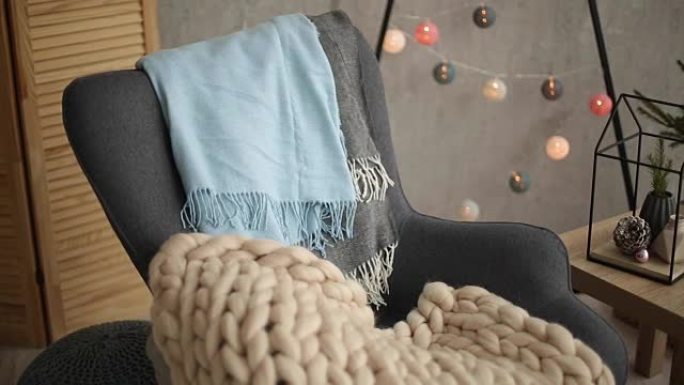 时尚的圣诞斯堪的纳维亚内部，配有优雅的扶手椅和温暖的美利奴格子。北欧新年装饰舒适之家。简约的圣诞树，