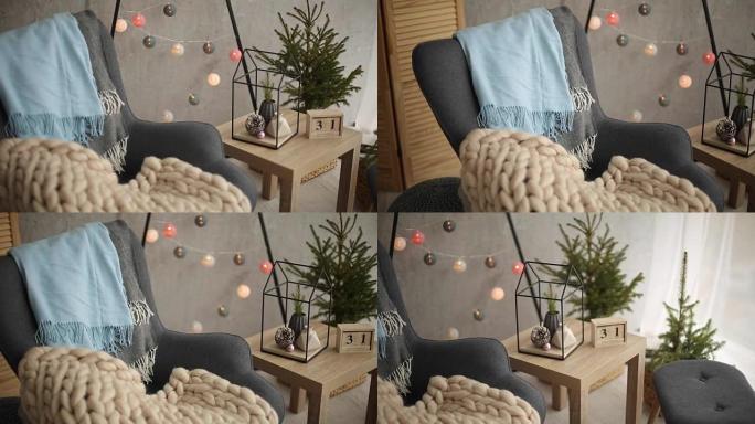 时尚的圣诞斯堪的纳维亚内部，配有优雅的扶手椅和温暖的美利奴格子。北欧新年装饰舒适之家。简约的圣诞树，