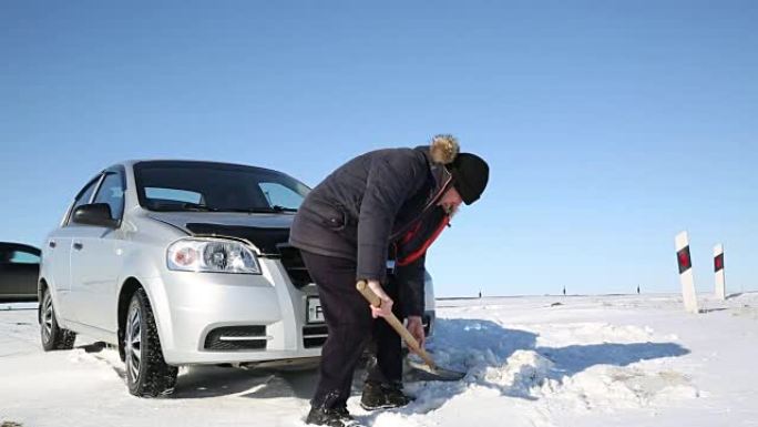 司机用铲子从雪地上挖出汽车。