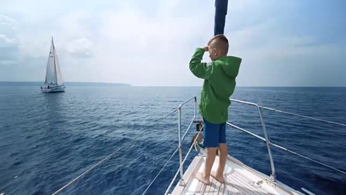 小男孩站在游艇的船头，向