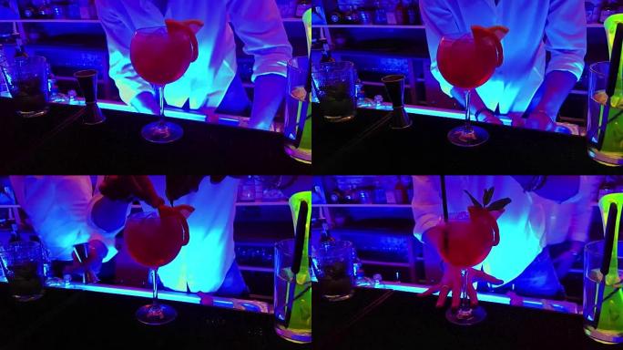 酒保在迪斯科酒吧的桌子上用柠檬片在玻璃杯中准备红酒精鸡尾酒饮料，俱乐部的气氛和乐趣
