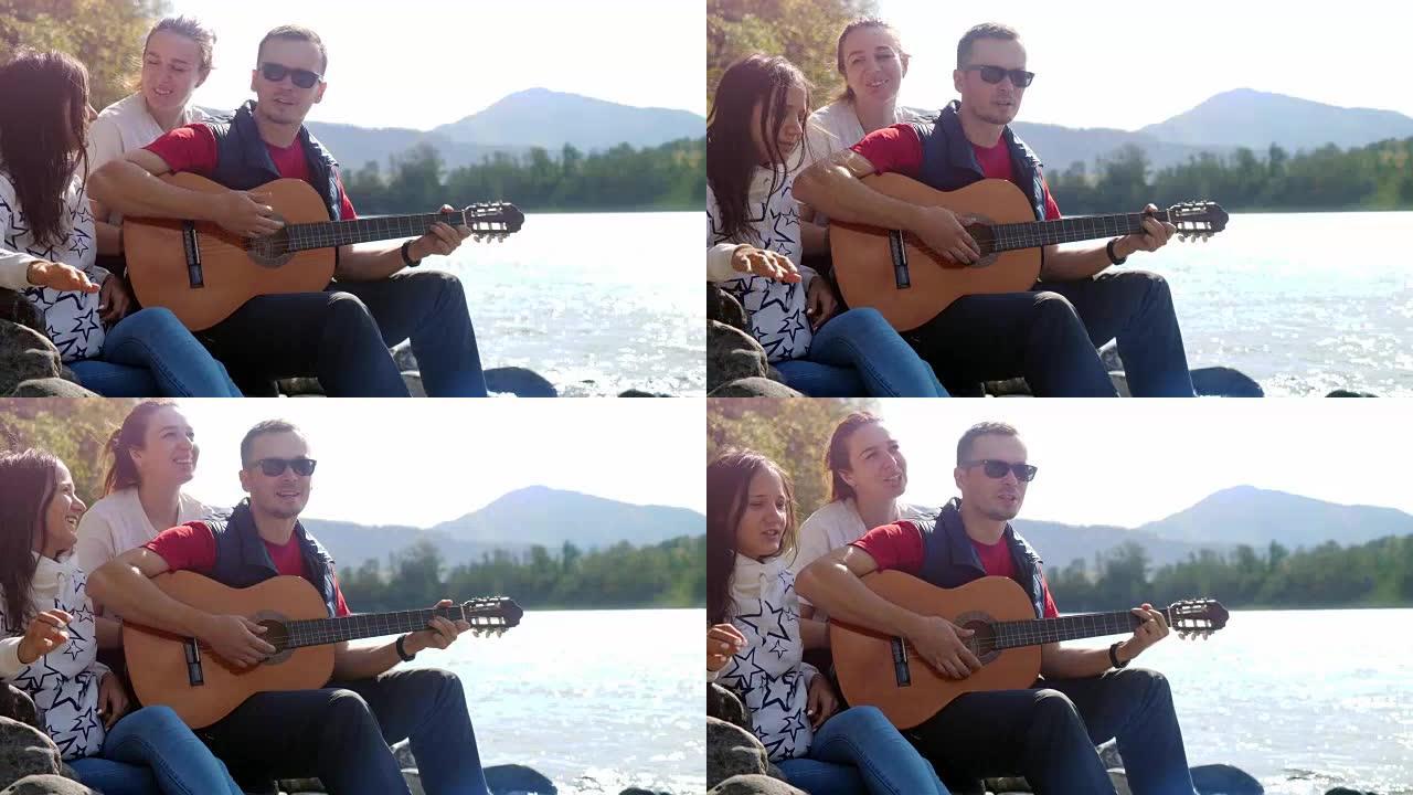 一群快乐的朋友在海边的夏天在山河旁边弹吉他唱歌。3840x2160