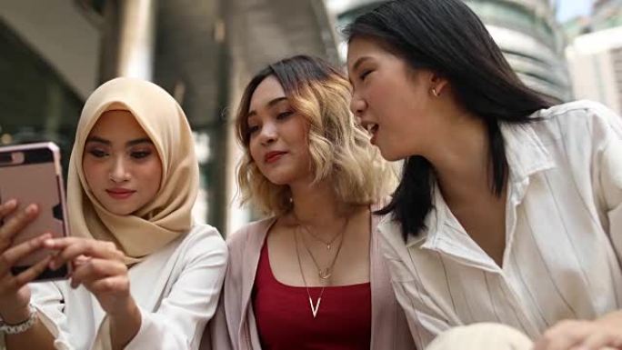 在国油塔前使用智能手机的多种族妇女