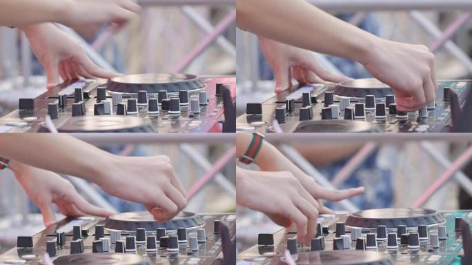特写DJ在DJ控制台上工作，增加音量。