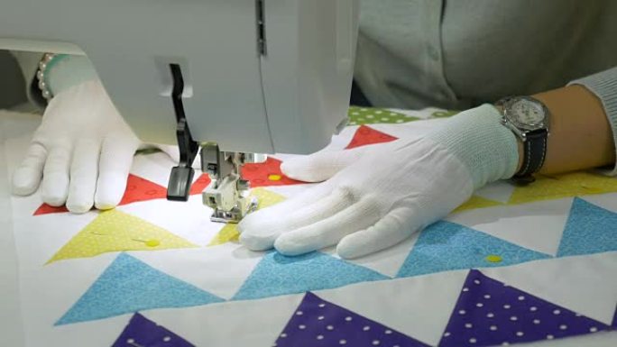 在缝纫机上工作。一个戴着白手套的女人在织物上涂鸦。