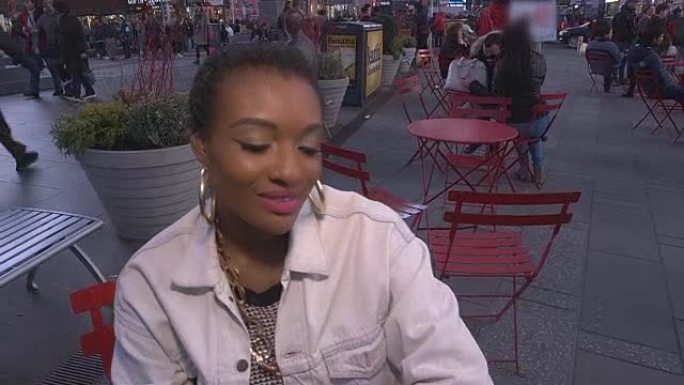 年轻的非洲裔美国妇女在纽约市时代广场的手机上发短信时显得愚蠢和情绪化