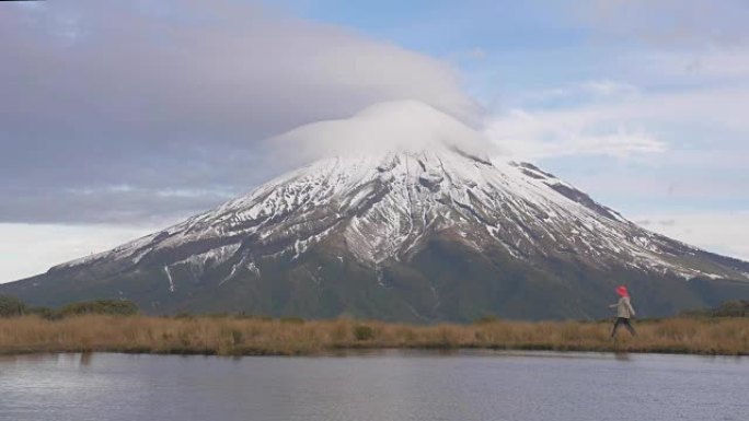 慢动作-旅行者向新西兰北岛的塔拉纳基火山望去，并在湖中反射tho山和登山者。新泽兰