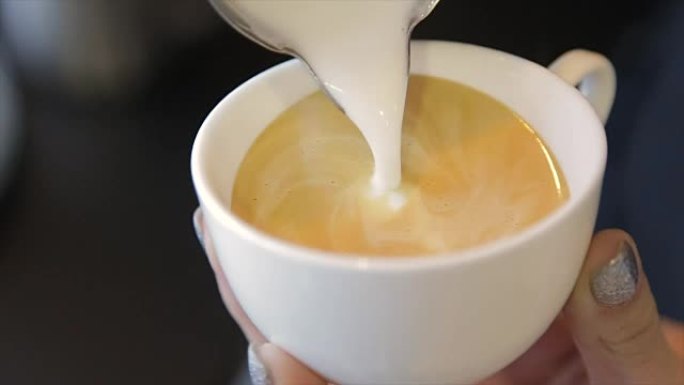 咖啡师将新鲜牛奶倒入咖啡中。卡布奇诺。