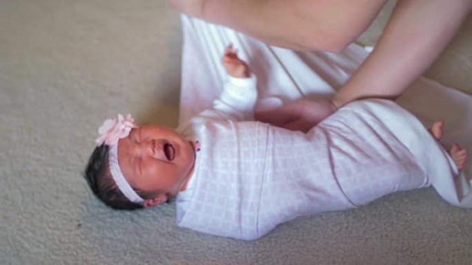 一位父亲用毯子包裹着刚出生的婴儿，然后抱起她