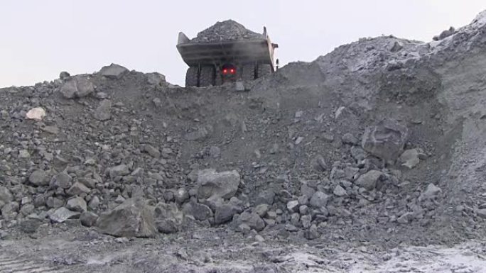 一辆大型自卸车将50吨矿石倒入悬崖。