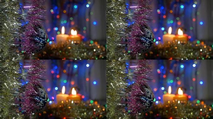 圣诞树上挂着一个蓝色的大球。新年和圣诞装饰品。燃烧蜡烛。闪光花环。背景模糊。