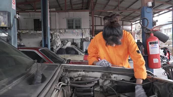 dolly shot: 亚洲年轻的女汽车修理工正在检查车辆发动机的一部分