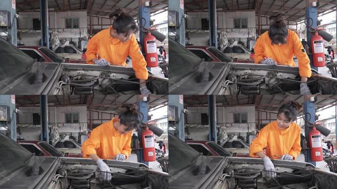 dolly shot: 亚洲年轻的女汽车修理工正在检查车辆发动机的一部分