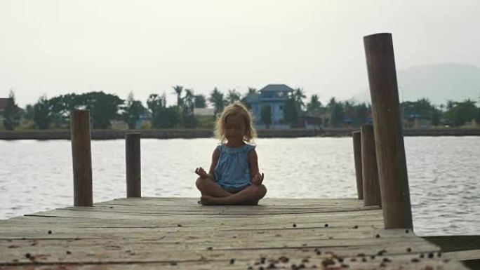 女童以莲花姿势坐在木墩上，以慢动作冥想