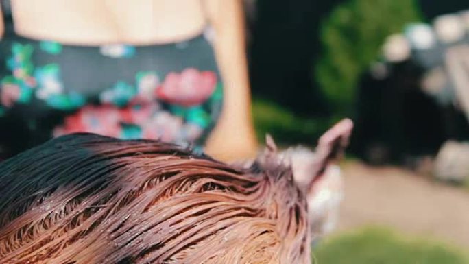 夏天，女人在街上用棕色油漆涂头发。在家染发