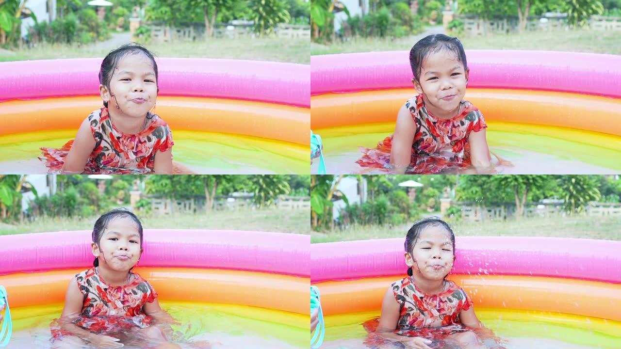 快乐的亚洲女孩从嘴里吹水，在夏天的橡胶池里玩水，慢动作镜头