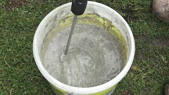 用电动搅拌机在桶里搅拌石膏。在桶里用搅拌机搅拌水泥。