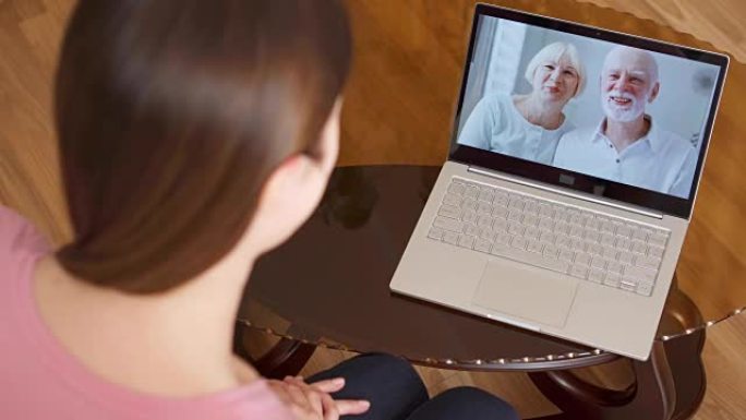 出国留学的女儿通过messenger应用程序与她的父母在笔记本电脑上进行视频聊天