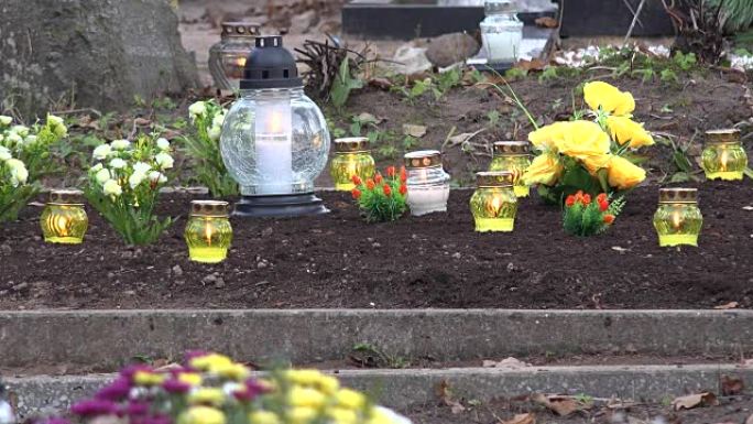 黄色的蜡烛在墓地的坟地上燃烧。FullHD