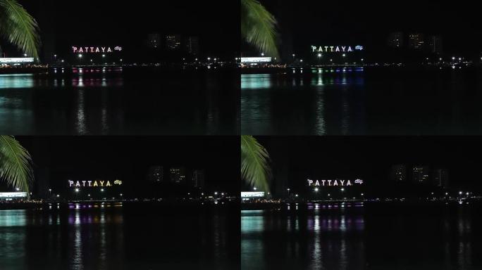 夜晚岩石上刻有芭堤雅铭文的海边景色。视频。夜晚芭堤雅湾海景。泰国春武里府芭提雅市鸟瞰图夜景