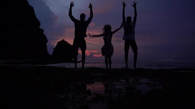 海洋上方的日落。朋友跳起来玩得开心