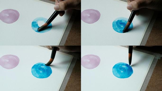 艺术家用画笔在水彩纸上300 GSM的水彩画蓝色cercal的特写镜头。