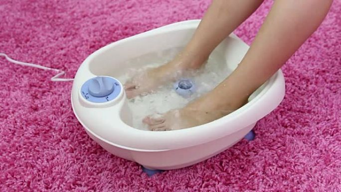 振动足部水疗按摩器中的女性脚。开关模式电动按摩足浴。