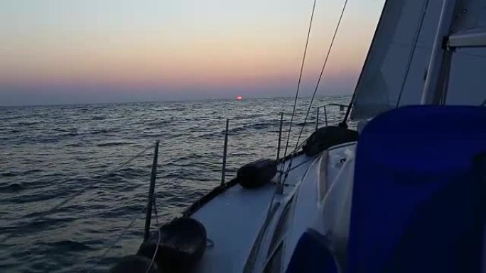 从帆船甲板上看，索具和预见轮廓映衬着灿烂的日落或日出的天空