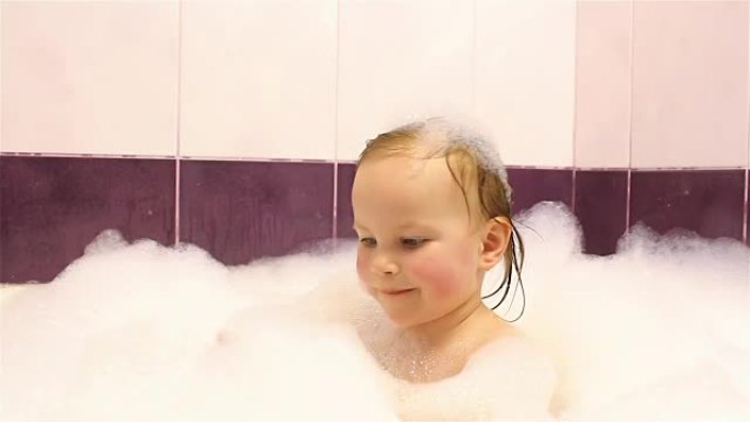 快乐的小女孩用泡沫在浴室洗澡。他玩泡沫