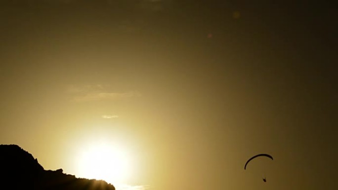 滑翔伞在日落时练习滑翔伞运动，背光