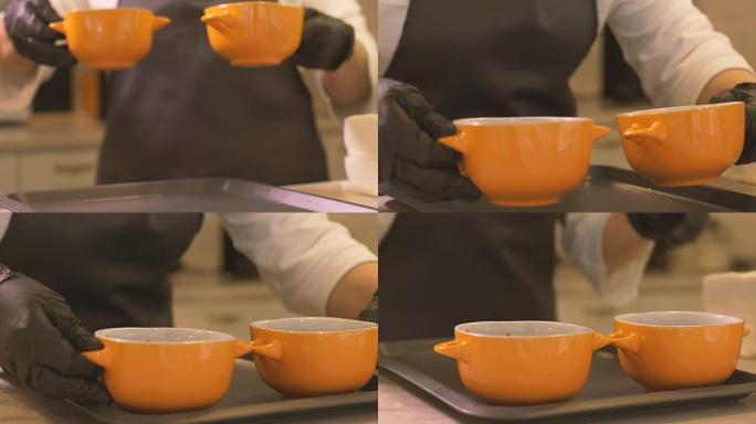 女人做饭把两个碗和热汤放在托盘上，供餐厅食用