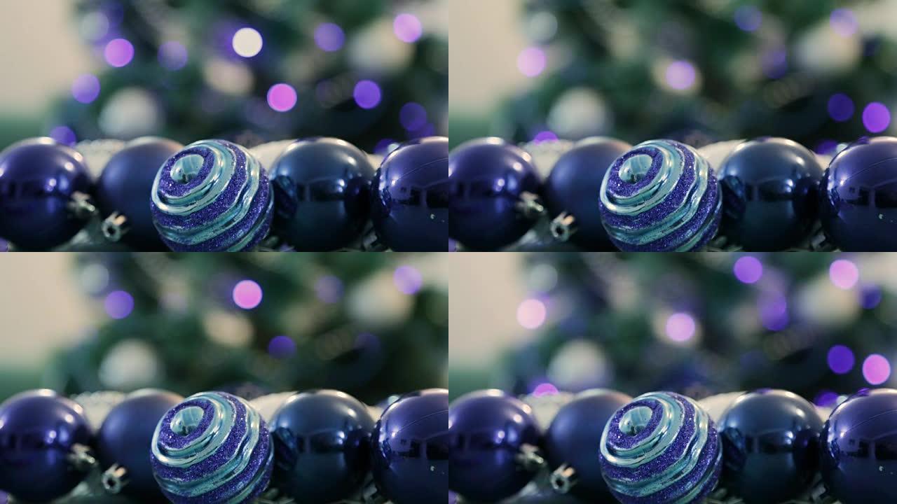 蓝色灯光装饰的圣诞树。前景中的圣诞球。背景中圣诞树的模糊图像