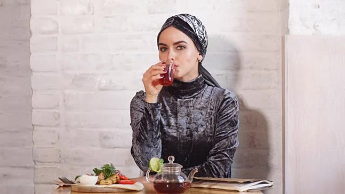戴着头巾的美丽穆斯林女孩在咖啡馆喝茶
