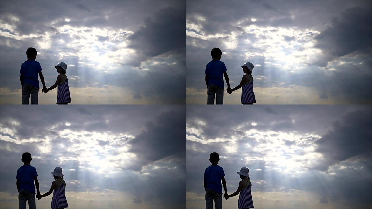 男孩与女孩牵手的背景下美丽的云彩在晚上