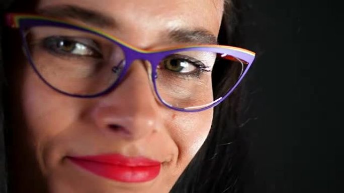 一个性感的黑发女人的肖像，嘴唇红红的，她在工作室里情色和嬉戏地尝试着时尚的眼镜、眼镜和性地看着相机。