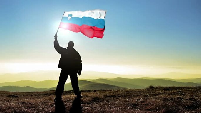 成功的剪影男子获胜者在山顶上挥舞着斯洛文尼亚国旗，4k电影院