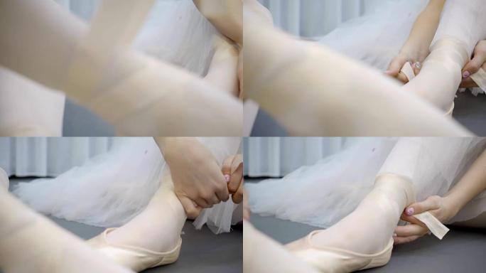 年轻的芭蕾舞女演员在芭蕾舞工作室的腿上绑上尖脚鞋的丝带