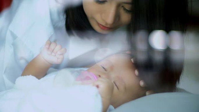 亚洲婴儿睡眠和年轻母亲在额头上亲吻