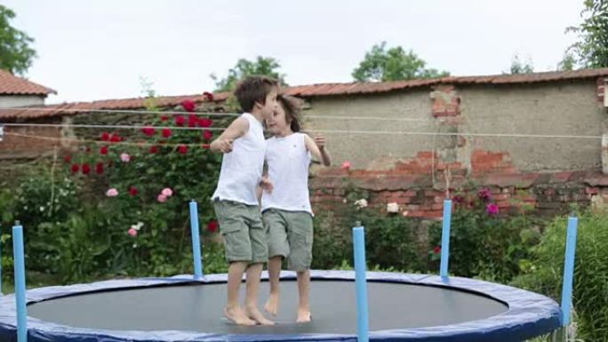可爱的孩子，兄弟们，夏天在花园里蹦床上跳。