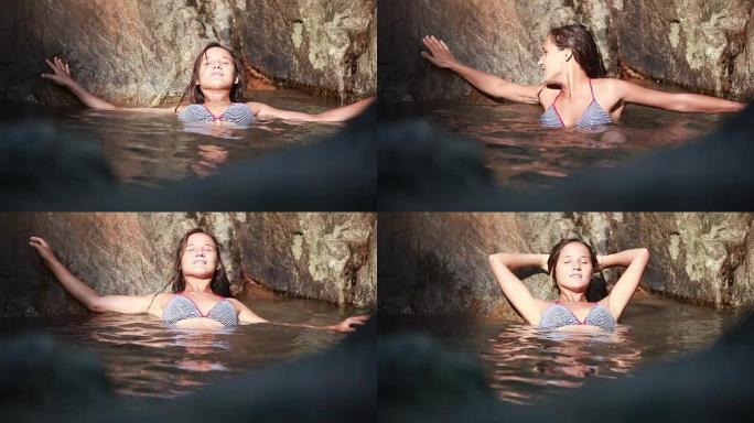 年轻美丽的女人在热带丛林的瀑布旁在水中放松。1920x1080