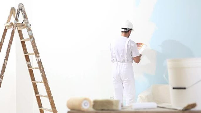 工作中的画家与色板样本，壁画概念，背景中的梯子和前景中的画笔和水桶